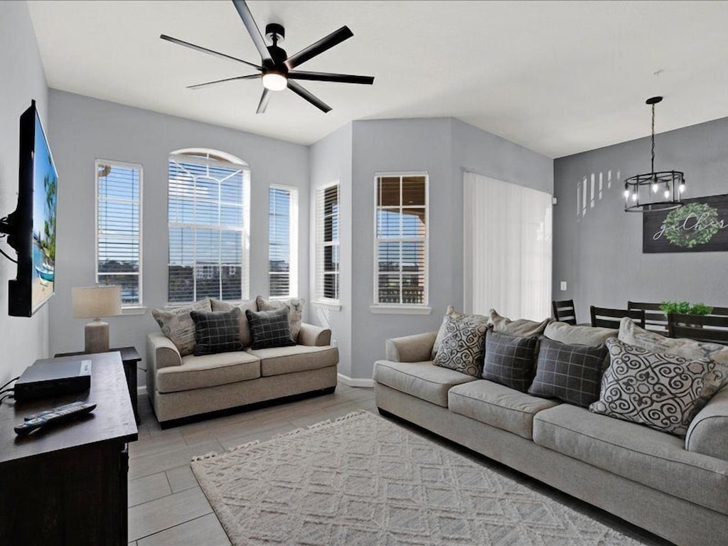 Bright living room with gray sofas and ceiling fan at Sunshine Terrace Villa