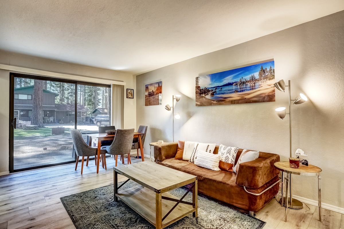 Wood-paneled living room with sofa and forest view at Emerald Bay Gateway