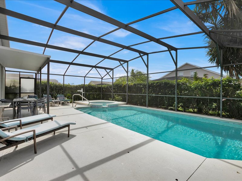 Sunlit private pool beside loungers under the screened enclosure at Poolside Villa
