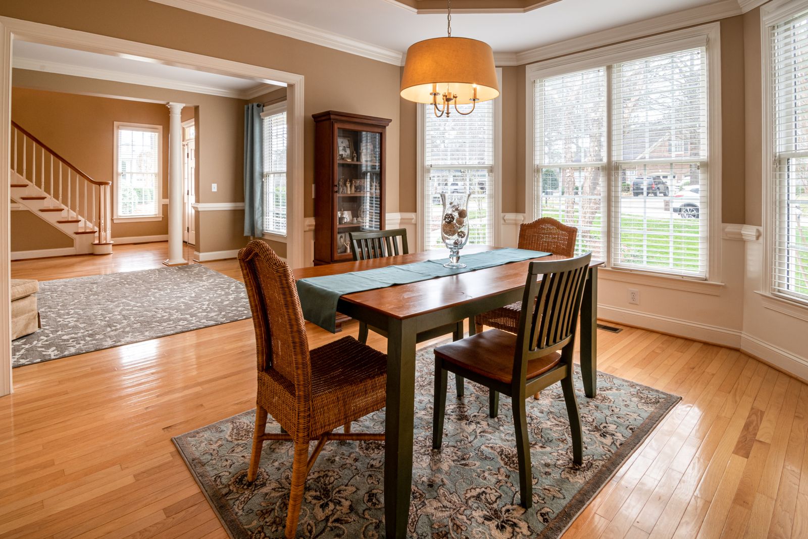Sunlit dining room with a long wooden table and wicker chairs