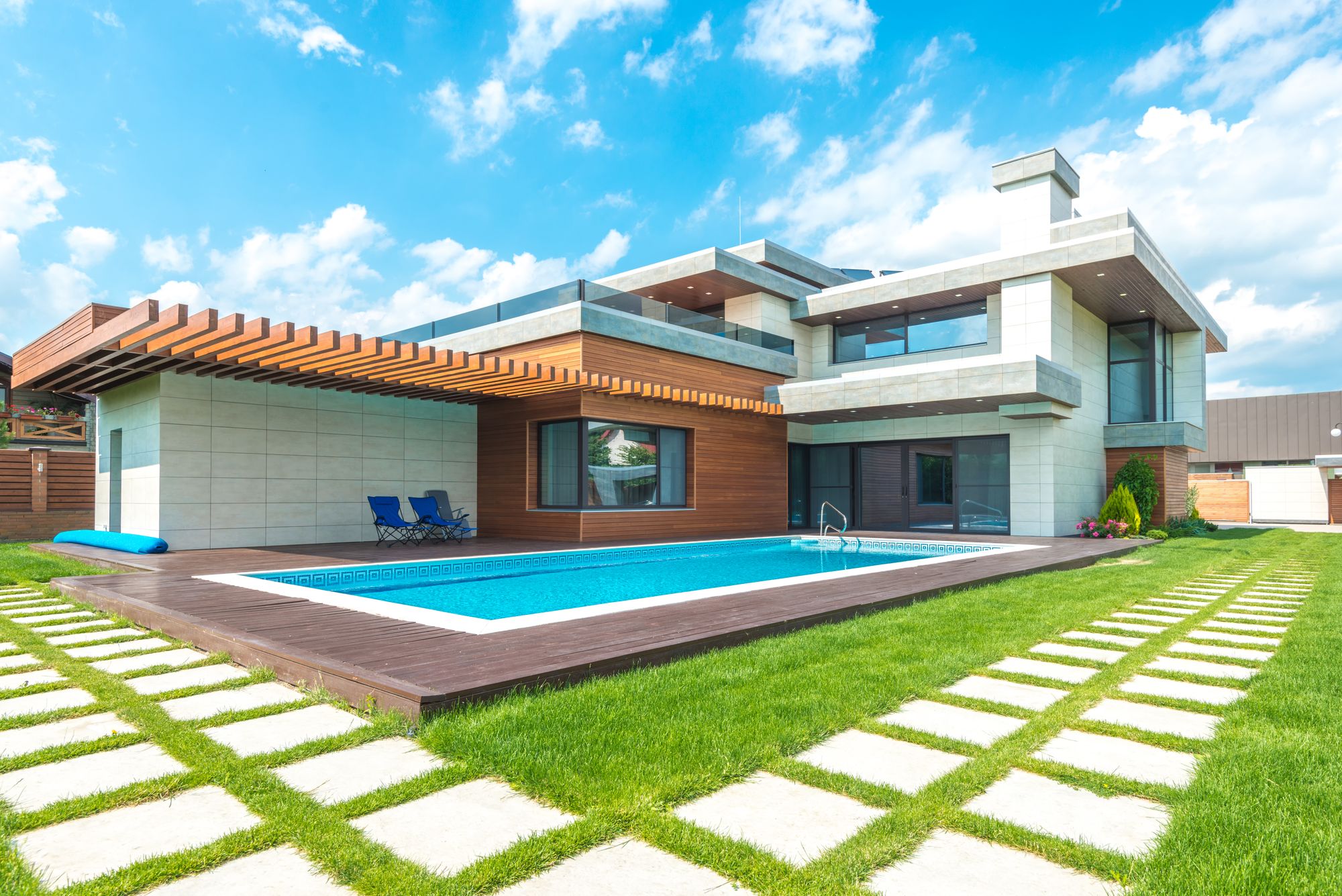 Sunny contemporary pool home with a green lawn under clear skies