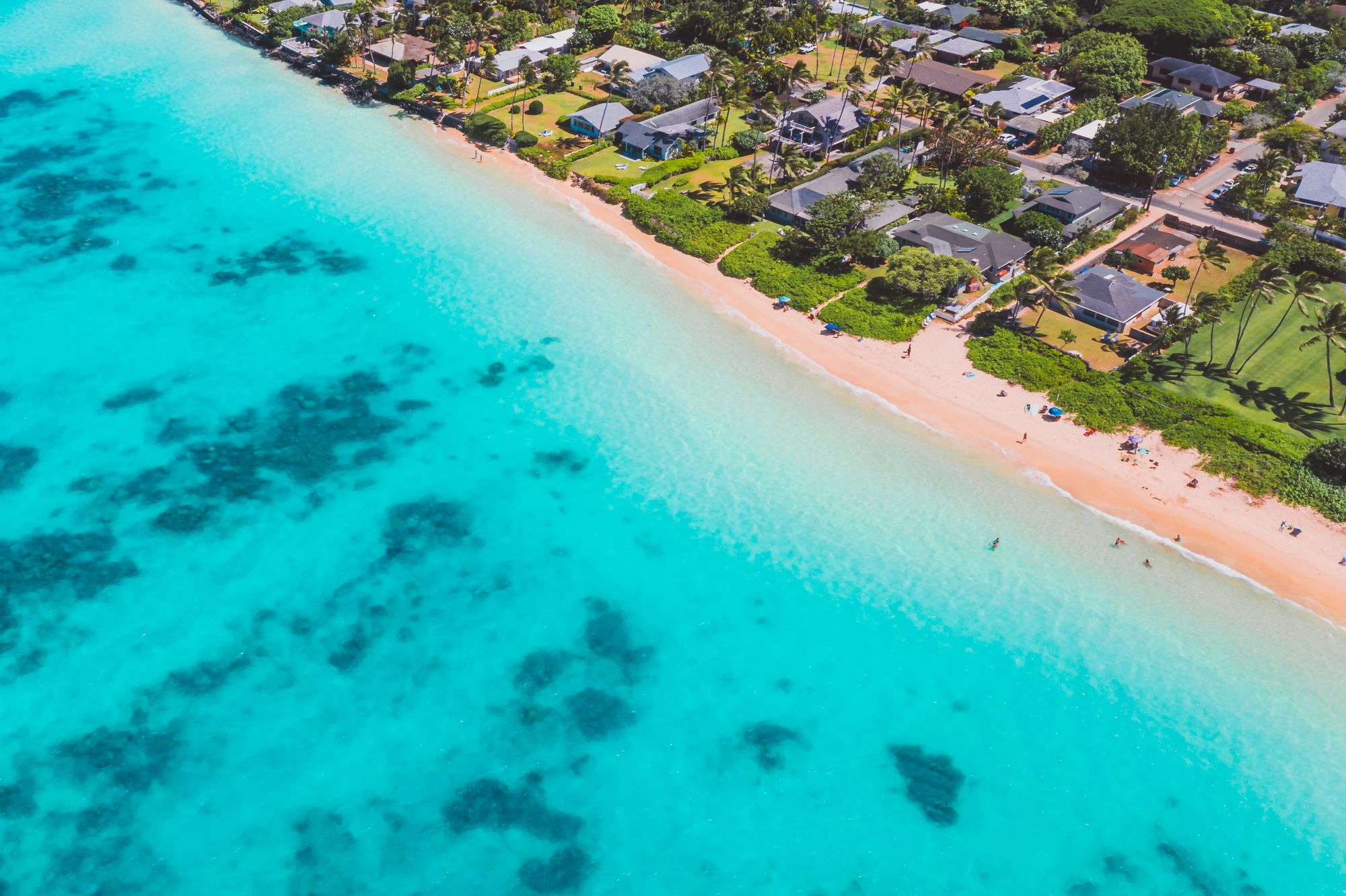 Homes along a turquoise bay under a bright sky