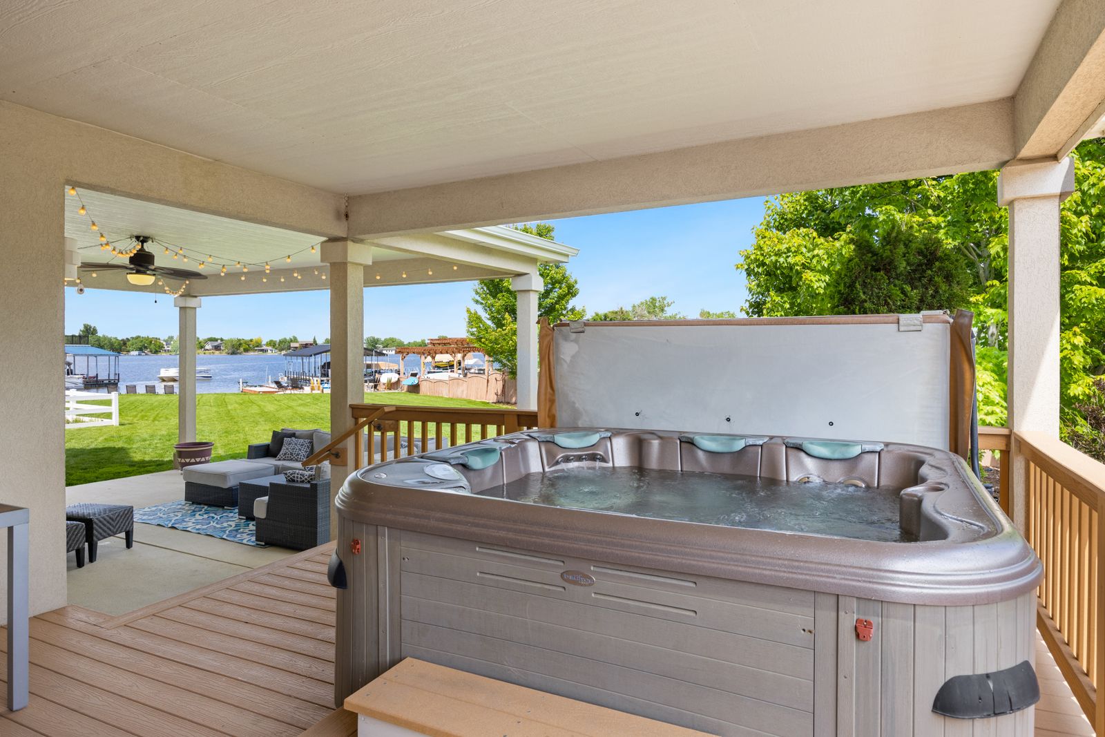Covered cabin deck with a hot tub overlooking water