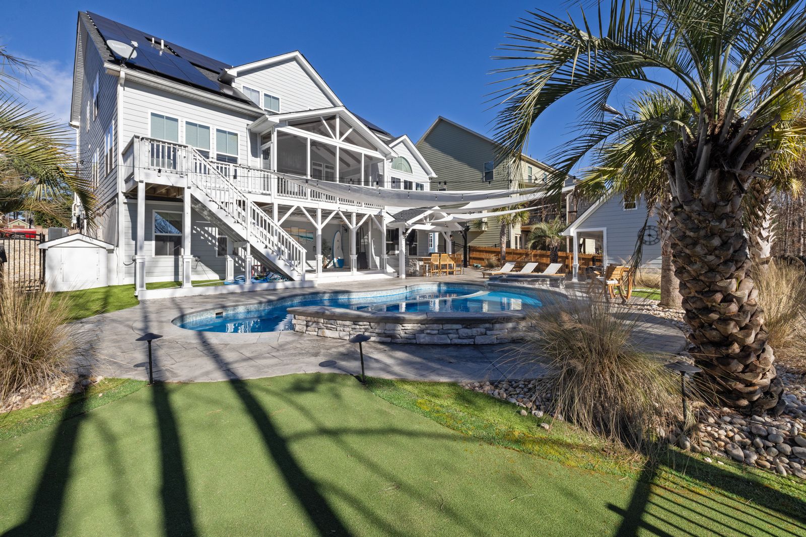 A sunny backyard pool with loungers and palms