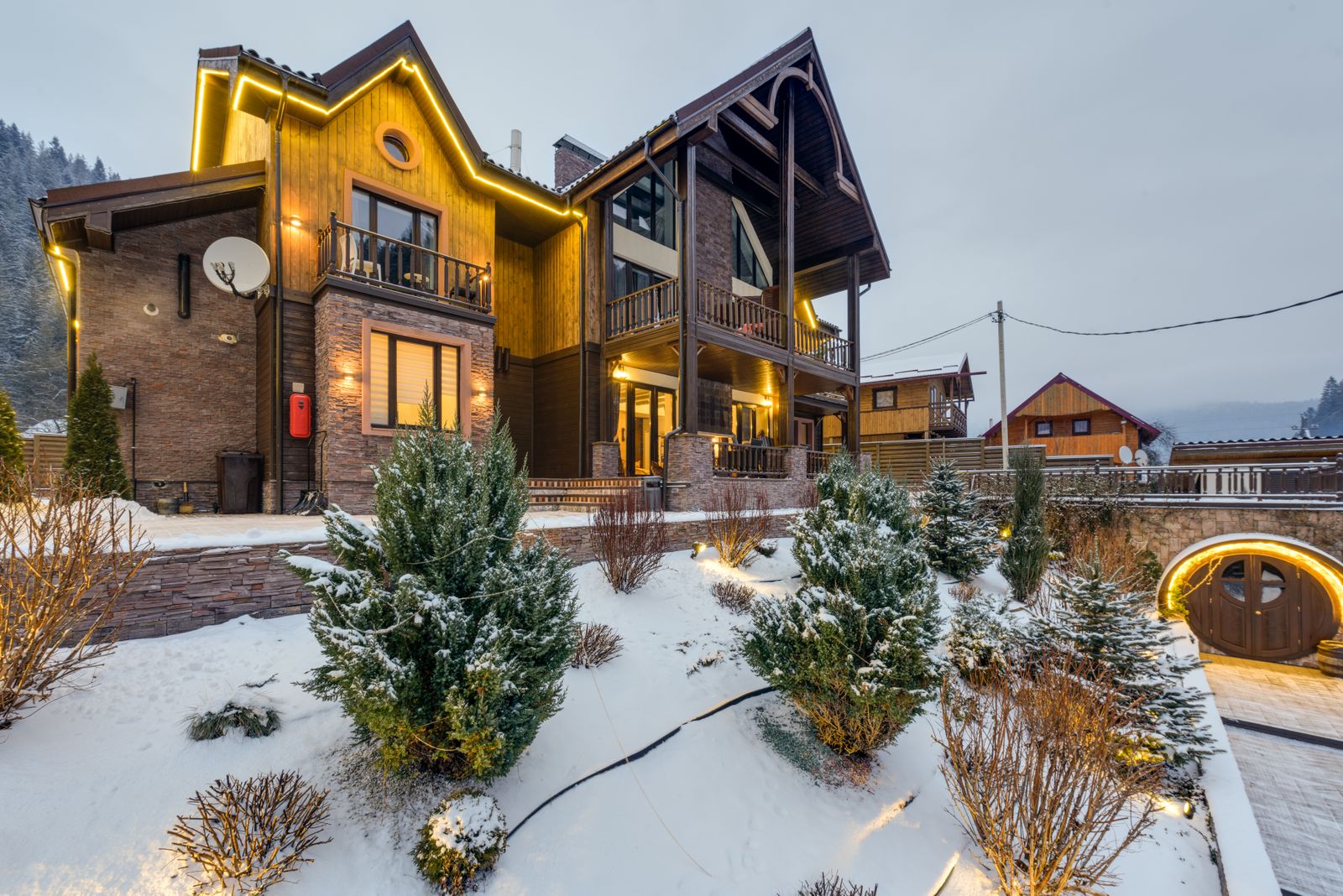 Warmly lit chalet surrounded by snow and small pines