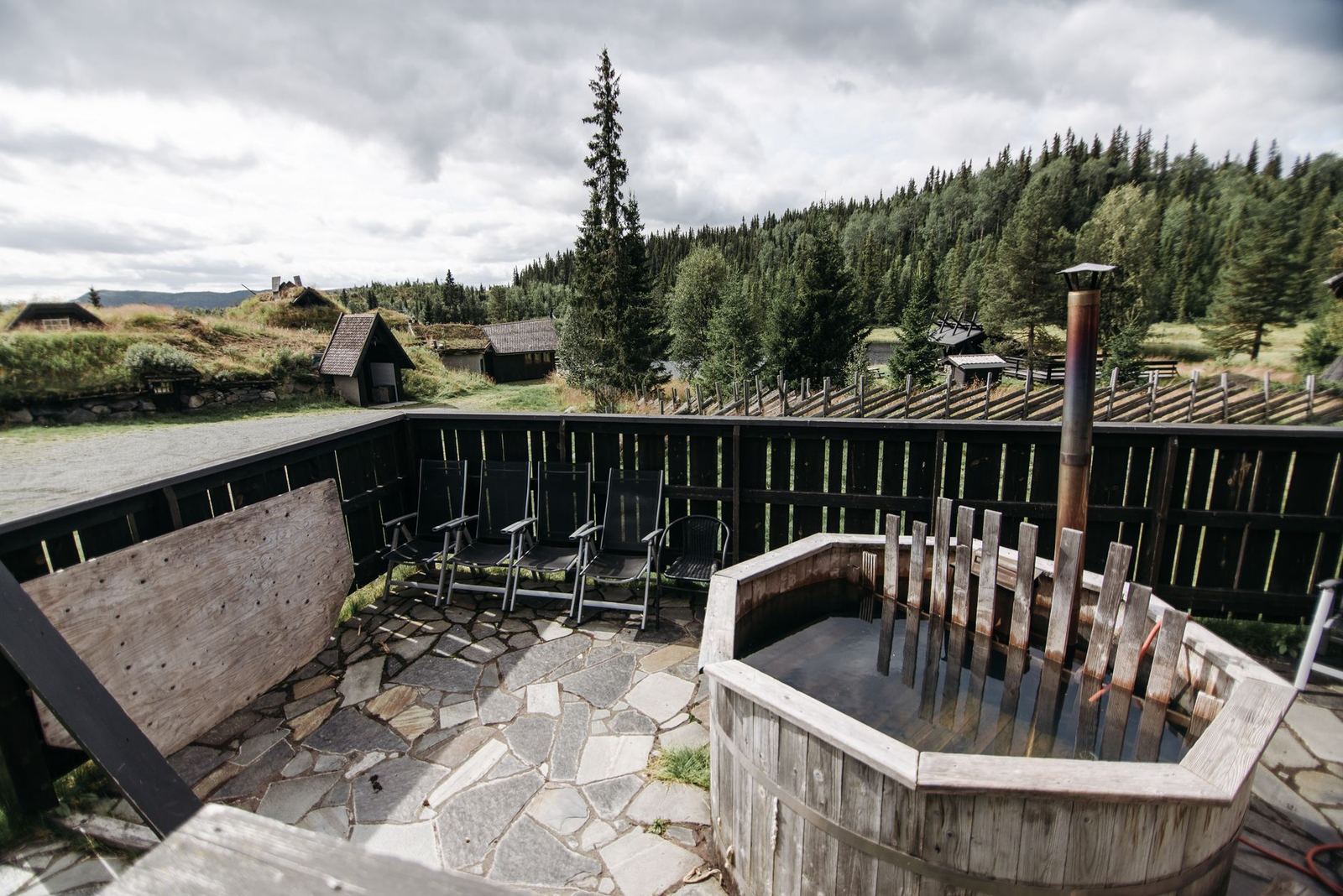 Wooden hot tub on a cabin patio with mountain forest views