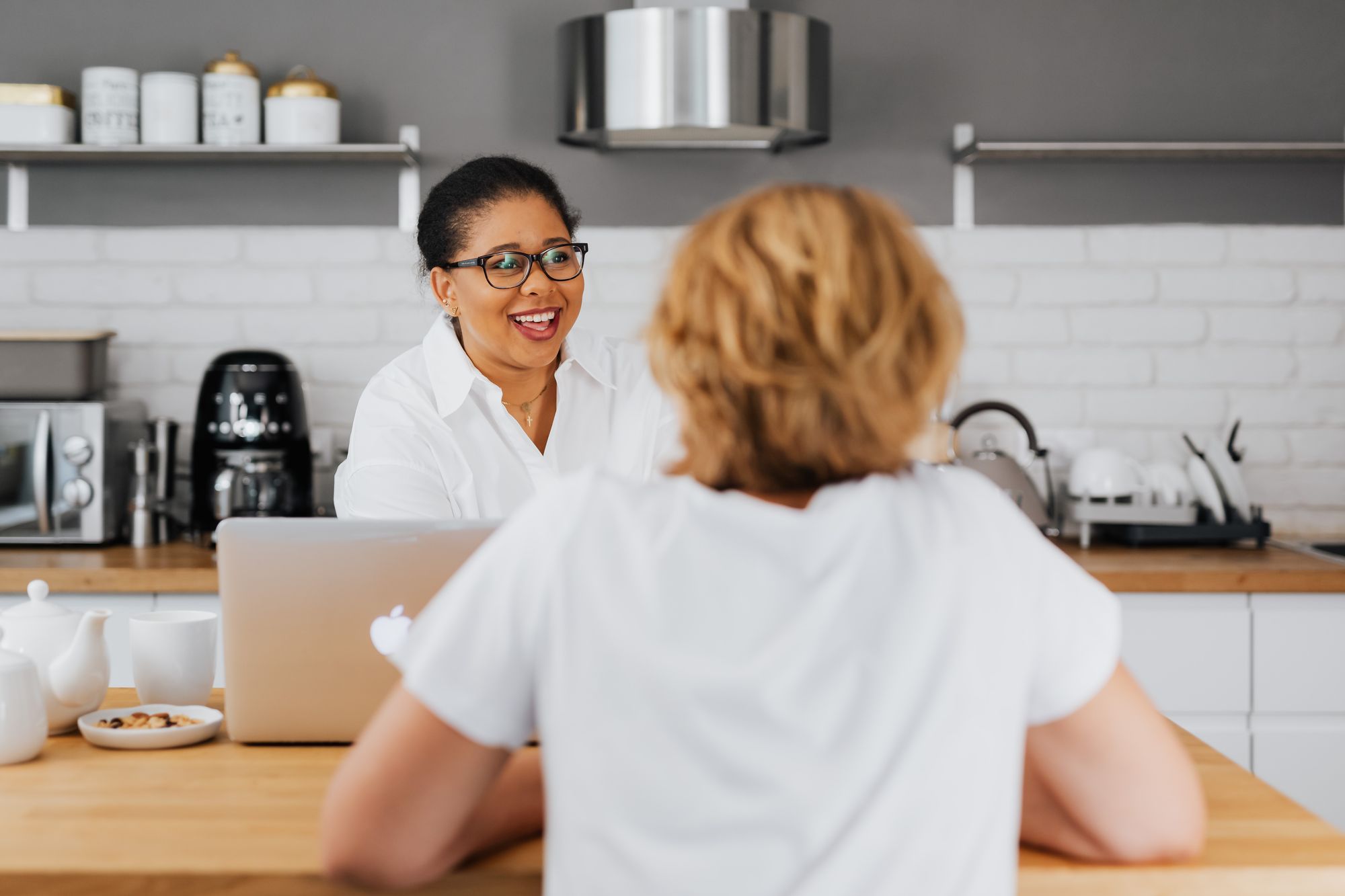 Two women talking at a bright kitchen table