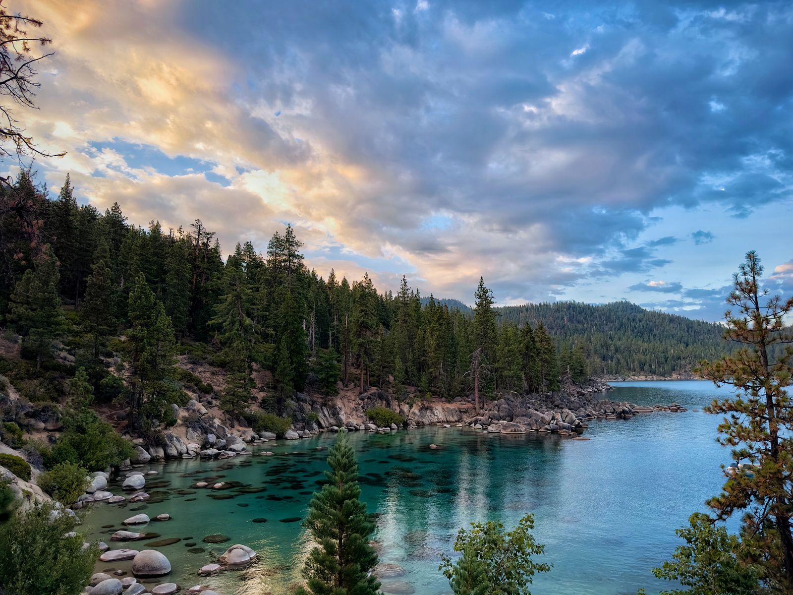 Lake Tahoe shoreline at sunset with forested slopes
