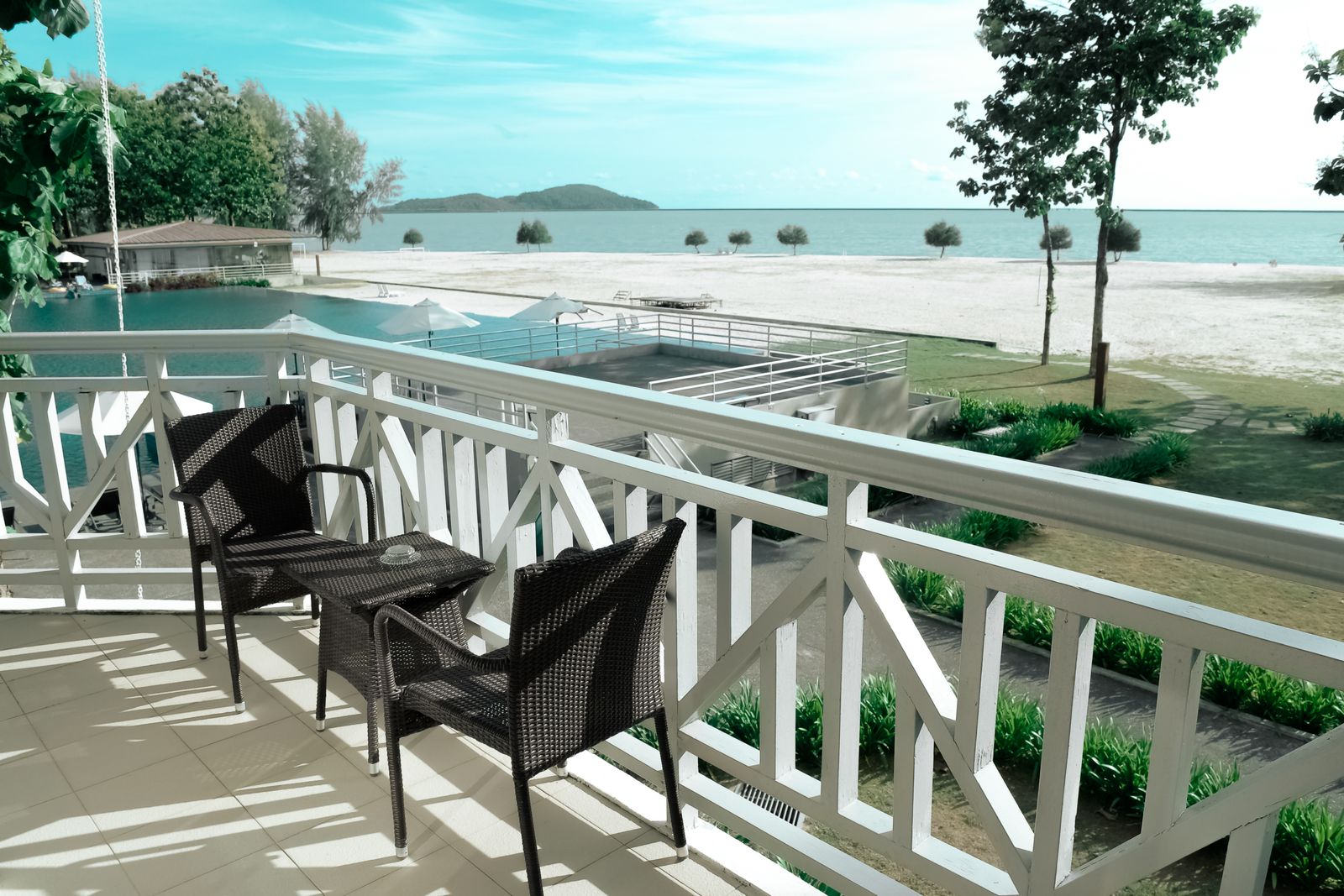 Bright lanai with chairs overlooking a pool and the ocean